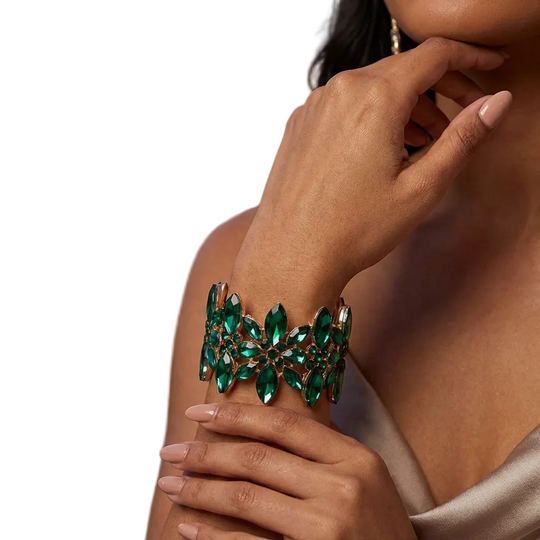 Close-up of a hand wearing a green gemstone bracelet with a blurred outdoor background.