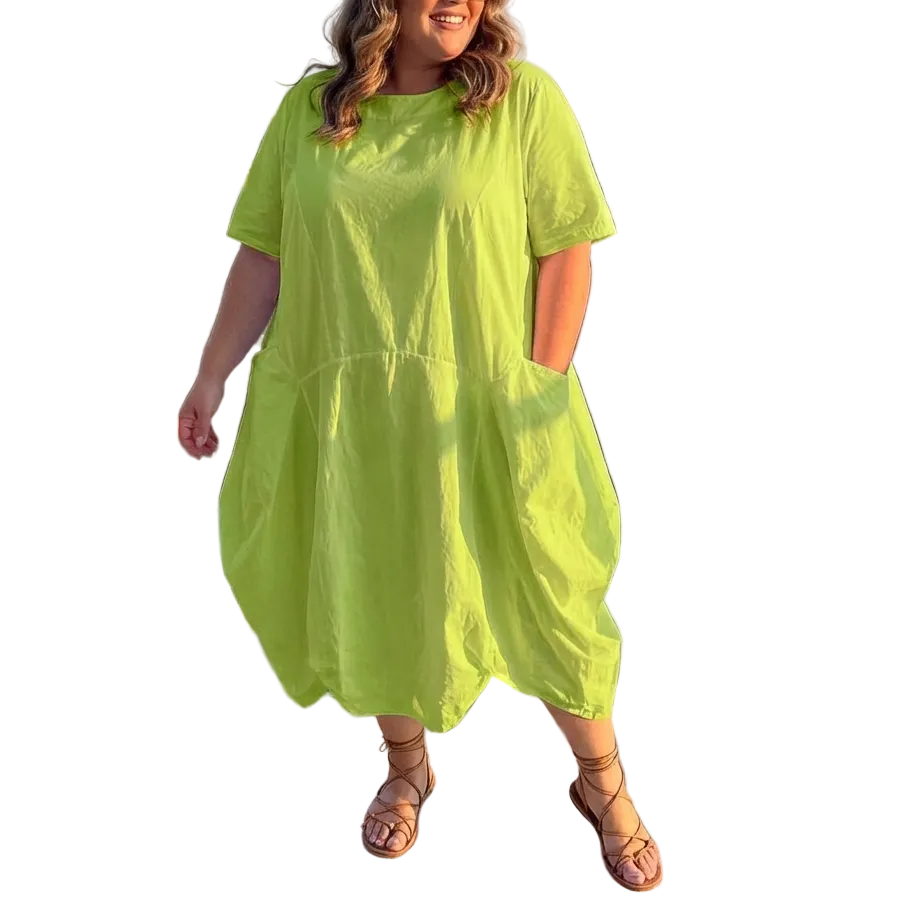 Woman in a bright green dress standing on a rooftop with cityscape background