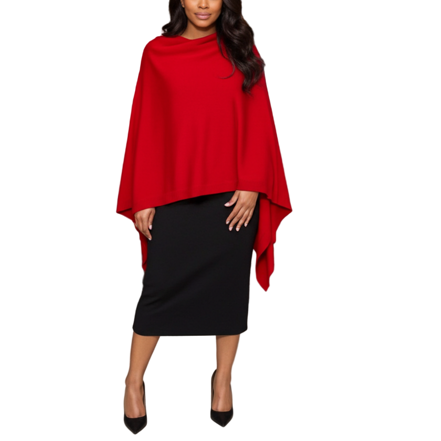 Woman wearing a red poncho over a black dress standing in front of a door.