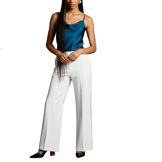 Model wearing a blue top and white pants being photographed on a gray background