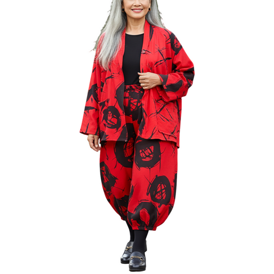 Woman in a red and black floral outfit walking outdoors on a path.