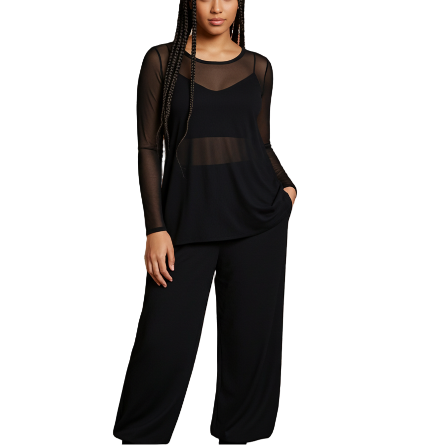 Woman wearing a black outfit standing against a brick wall