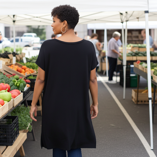 Woman walking through an outdoor farmers market with produce stands.