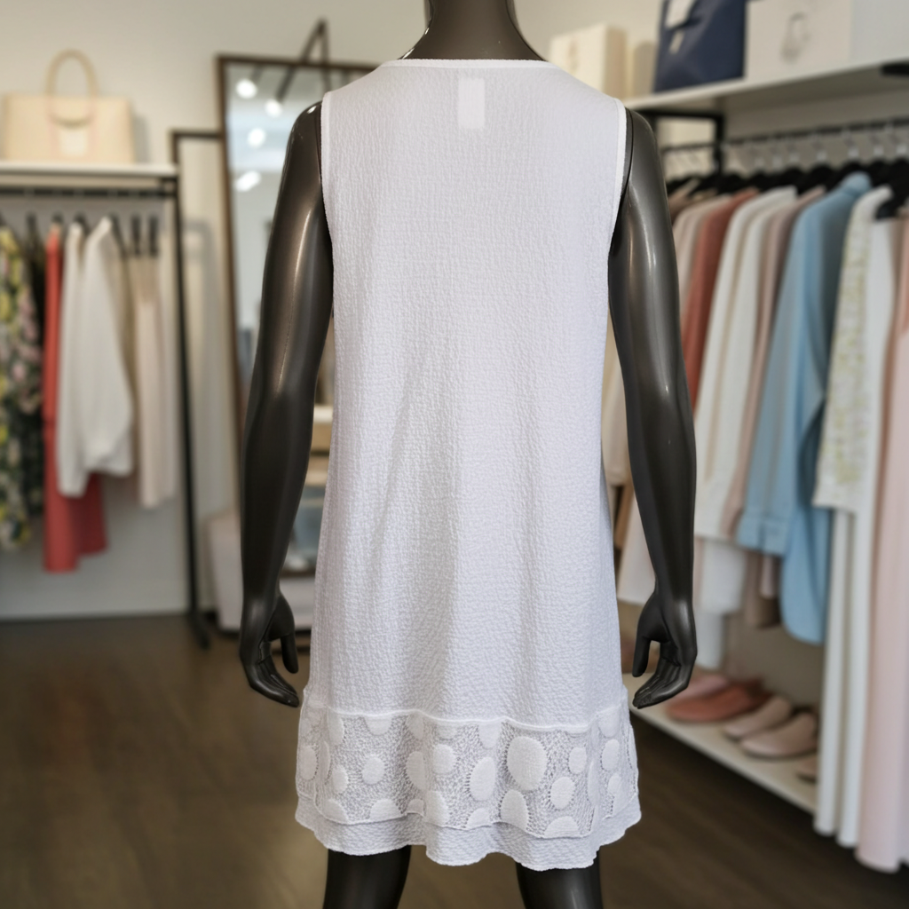Mannequin wearing a white sleeveless dress with lace details in a clothing store.