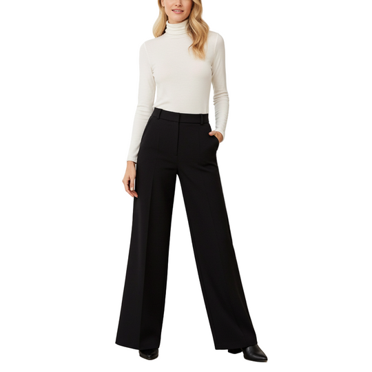 Woman wearing a white turtleneck and black wide-leg pants in a minimalistic room.