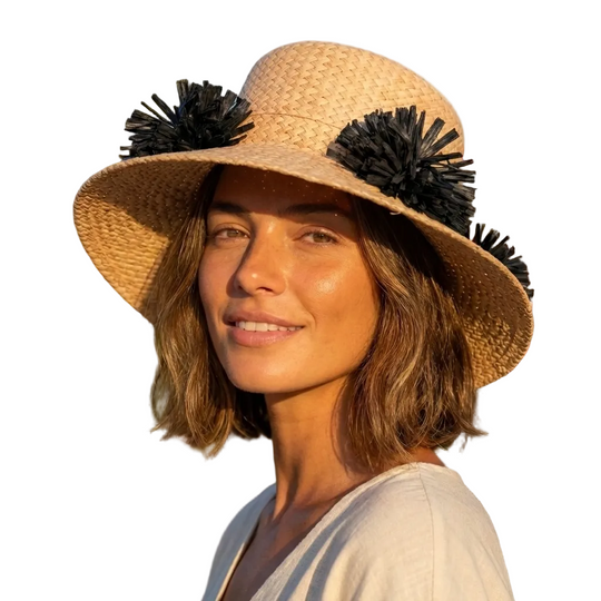 Woman wearing a straw hat with black decorative elements in a garden setting