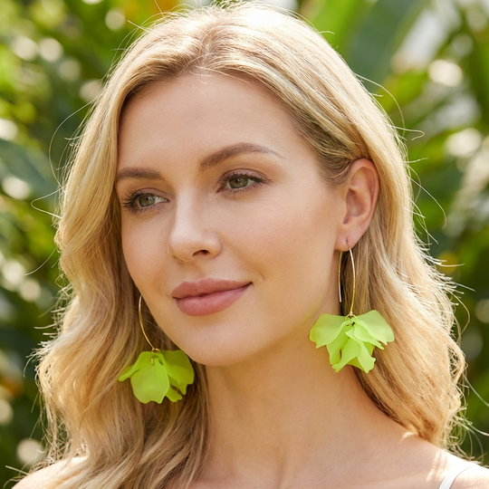 Woman wearing green leaf-shaped earrings with a blurred green background