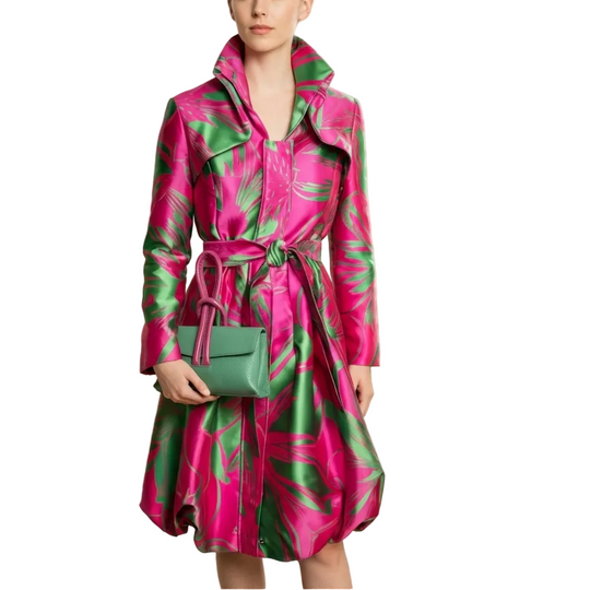 Woman wearing a pink and green patterned coat holding a matching handbag in a well-lit room.