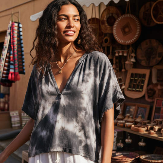Woman wearing a tie-dye shirt in front of a store with various items on display