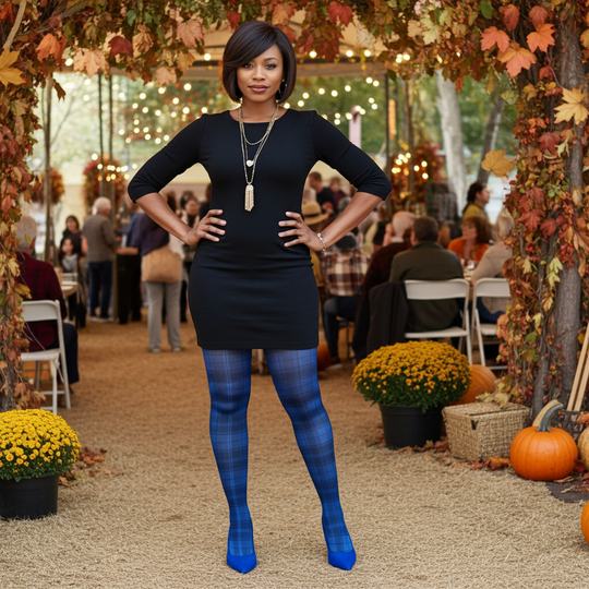 Woman in a black dress and blue tights standing in an outdoor setting with autumn decorations.