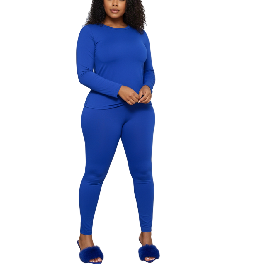 Woman in a blue outfit standing in a room with white curtains and a wooden floor.