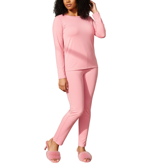 Woman in pink outfit standing in a bright living room with a plant and lamp in the background.