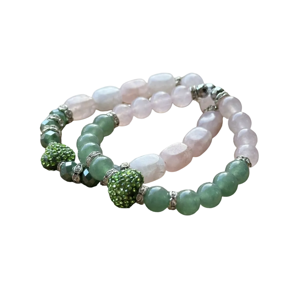 Two beaded bracelets with green and pink beads on a wooden surface