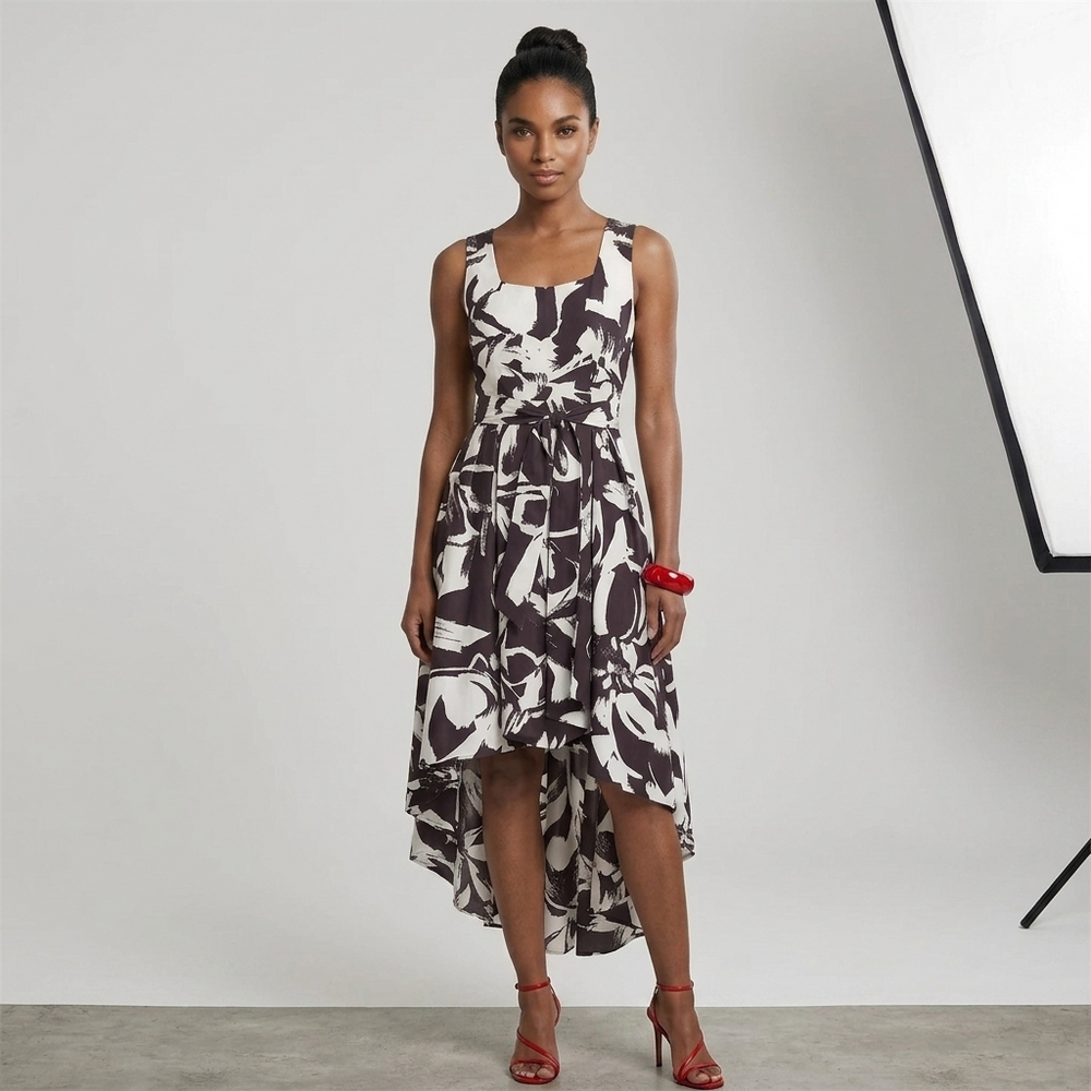 Woman wearing a white black sleeveless floral dress against a plain background