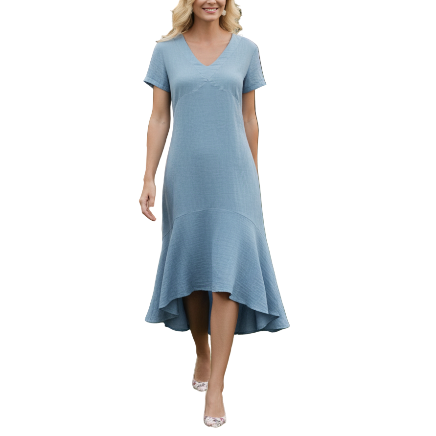 Woman in a blue dress standing in an outdoor setting with tables and decorations.