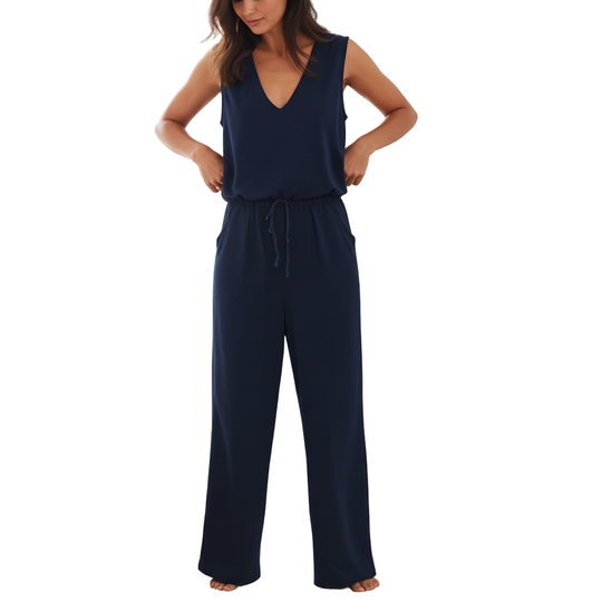 Woman wearing a navy blue jumpsuit in a bedroom setting.