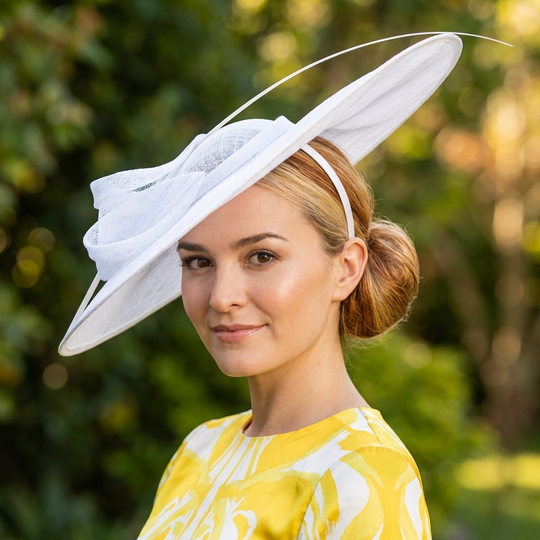 Woman wearing a large white hat with a blurred green background