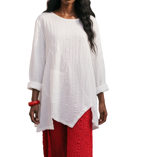 Woman in a white top and red pants standing among flower stalls.