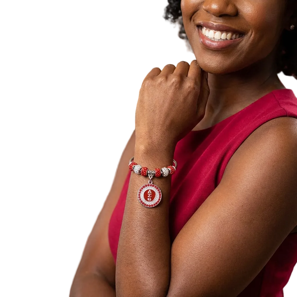 Woman wearing a red bracelet with a circular charm, smiling, with a blurred background of people and a table.