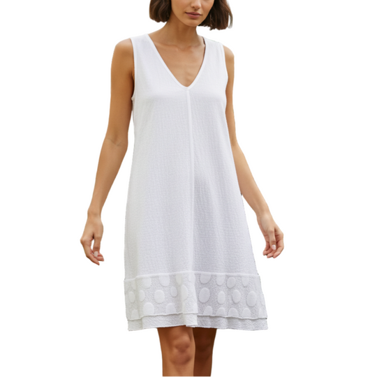 Woman in a white dress standing in a greenhouse filled with plants