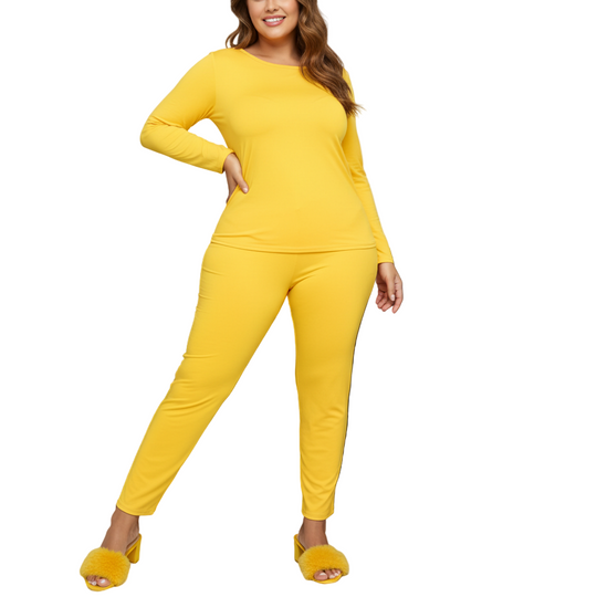 Woman in yellow outfit standing in front of a gray sofa with a plant to the side.