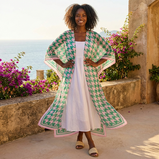 Woman walking outdoors in a garden wearing a green and pink and white patterned kimono-style garment.