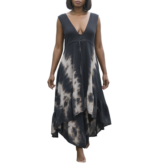 Woman in a black tie-dye dress walking through a greenhouse filled with plants.