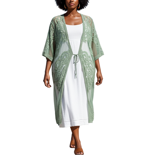 Woman in a green kimono over a white dress walking on a wooden boardwalk with palm trees in the background.