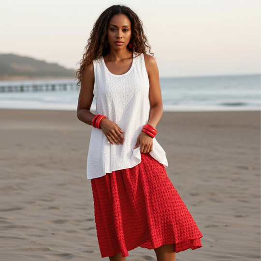 Woman wearing a white top and red skirt on a beach
