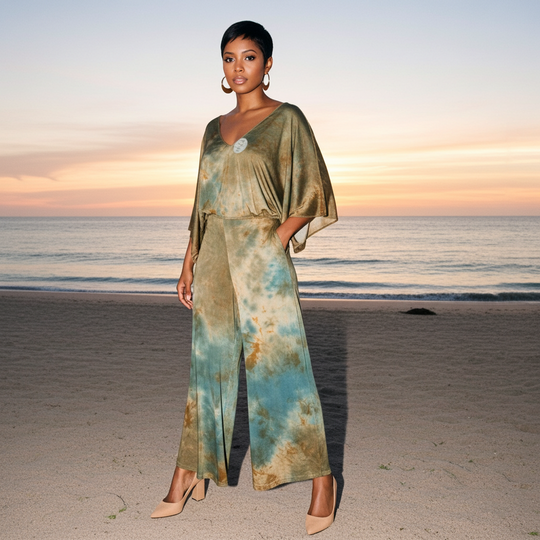 Woman in a tie-dye dress standing on a beach at sunset