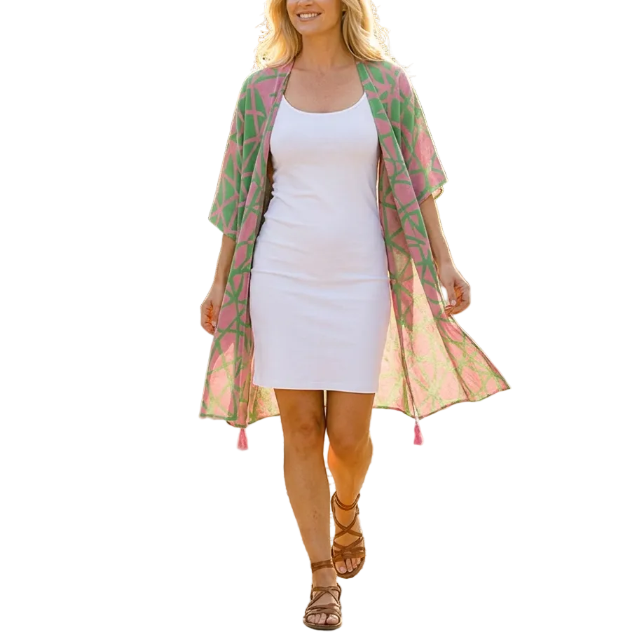 Woman in a white dress and pink floral kimono walking on a cobblestone path in a garden.