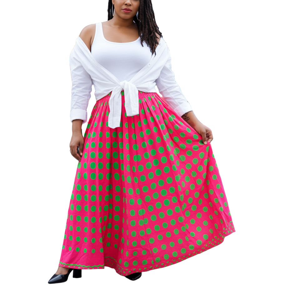 Woman in a white top and pink polka dot skirt standing in front of colorful graffiti.