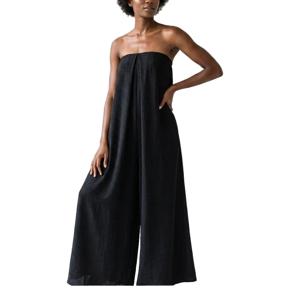 Woman wearing a black strapless jumpsuit against a white background