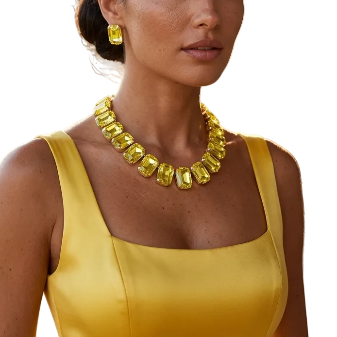 A woman wearing a bright yellow gemstone necklace and matching yellow earrings, styled with a yellow satin dress, set against a warm, sunlit outdoor background with stone columns and greenery.