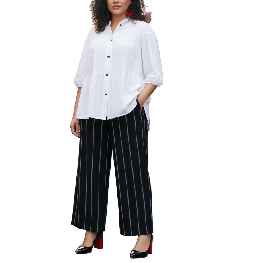 Woman in a white shirt and black striped pants standing in an outdoor market.