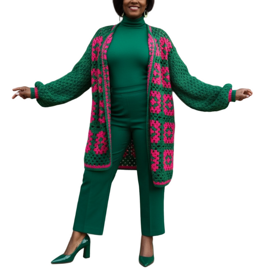 Woman in green outfit with pink patterned cardigan standing on steps outside a building