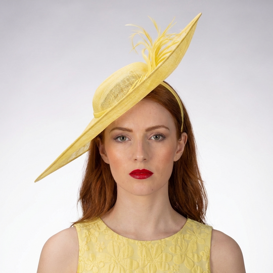 Woman wearing a yellow hat with feathers on a white background