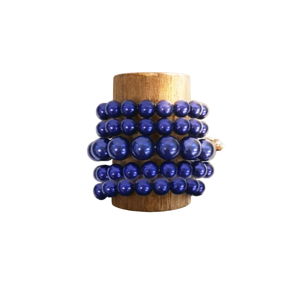 Stack of blue beaded bracelets on a wooden stand with jewelry on a rustic wooden surface.
