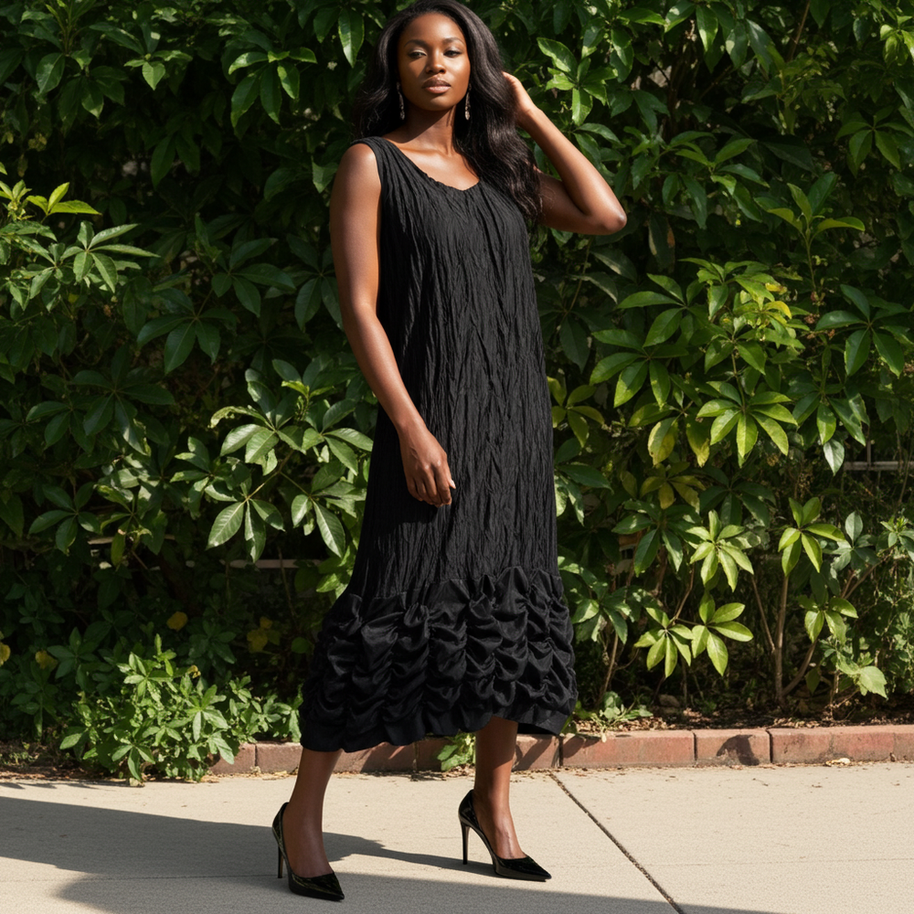 Woman wearing a black dress standing outdoors with greenery in the background