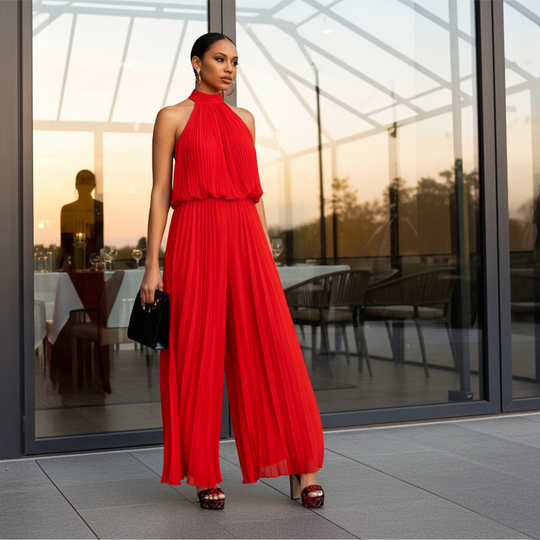 Woman in a red dress standing in front of a glass door with a sunset view.