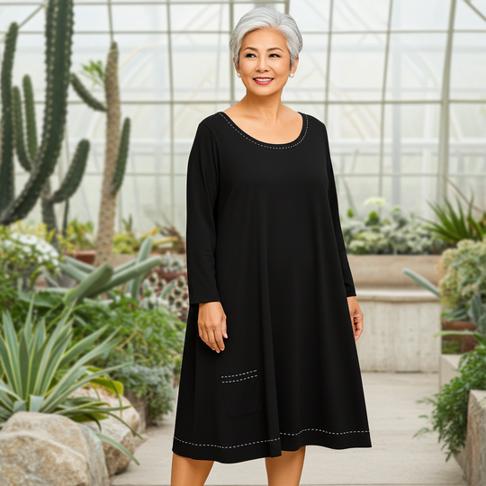 Woman in a black dress standing in a greenhouse with plants around