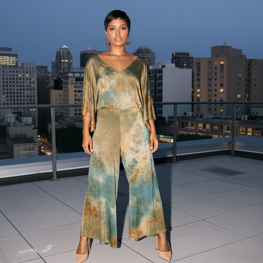 Woman in a tie-dye outfit standing on a rooftop with city skyline in the background