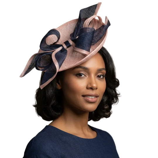 Woman wearing a decorative hat with pink and navy colors against a neutral background