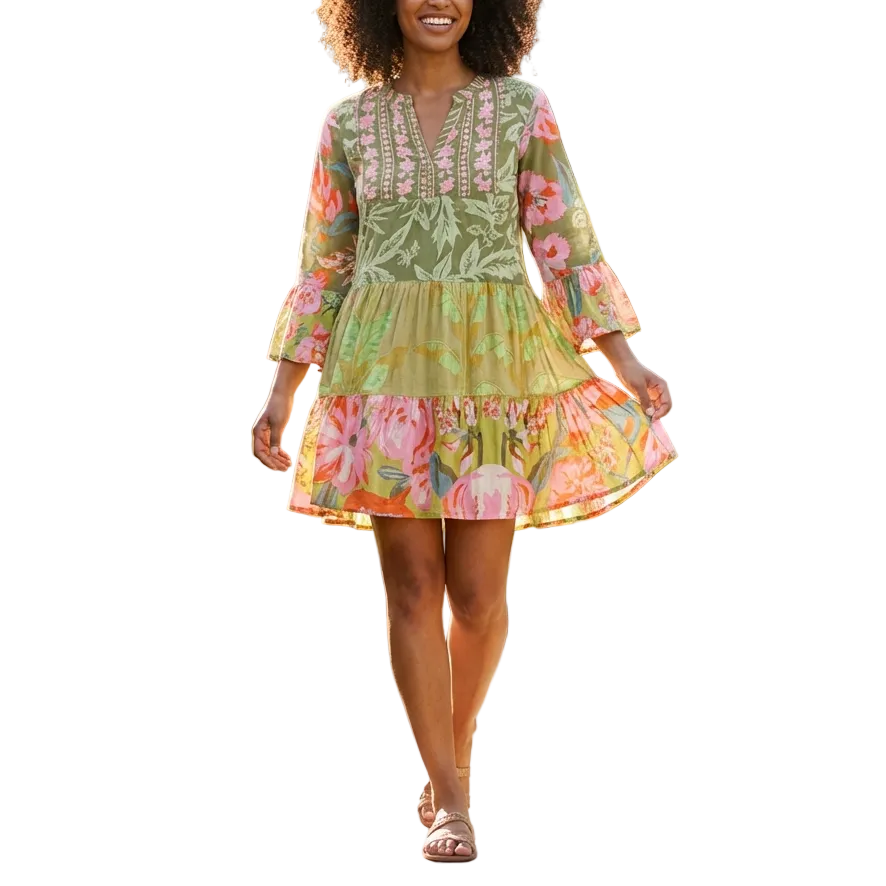 Woman in a floral dress walking through a garden with flowers and greenery.