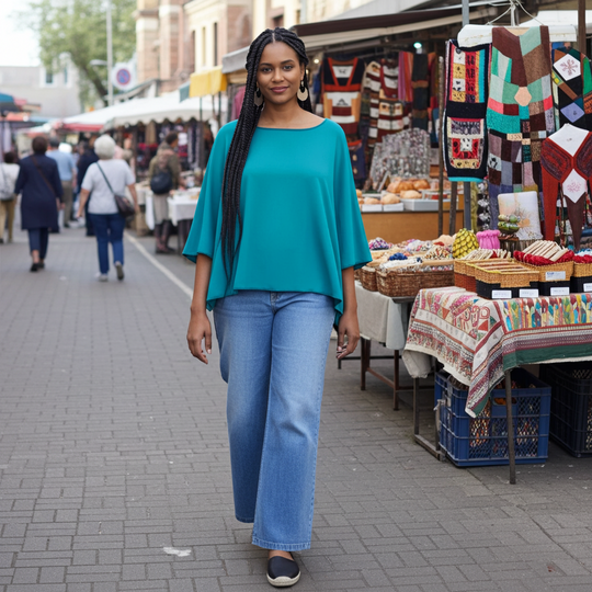 Woman in teal top and blue jeans standing in an outdoor market setting.