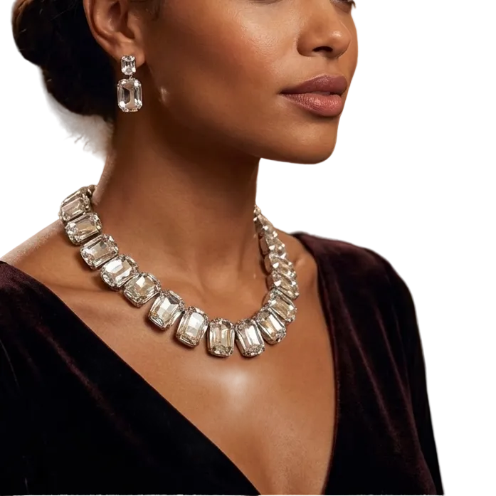 Woman wearing a sparkling necklace and earrings in an elegant indoor setting with chandeliers.