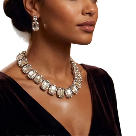 Woman wearing a sparkling necklace and earrings in an elegant indoor setting with chandeliers.