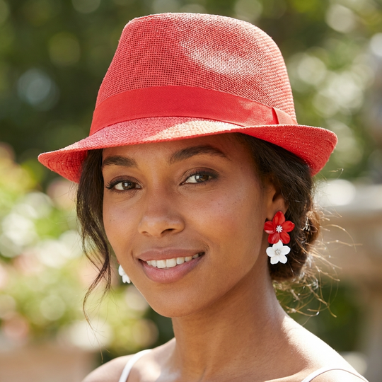 Woman wearing a red hat and flower earrings with a blurred green background