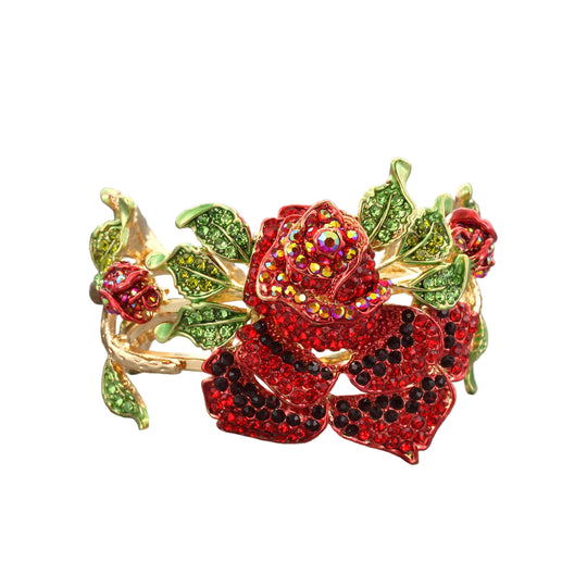 An oversized rhinestone bracelet with a gold tone finish, featuring a rose motif with red and green rhinestones.