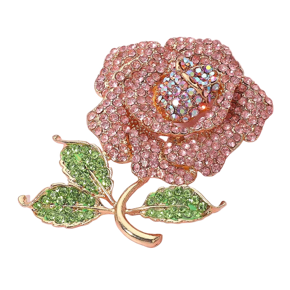 Decorative rose brooch with pink gemstones and green leaves on a pink background